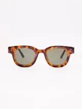 Lentes de sol con armazón grueso de acetato color carey (tortoise) y cristales oscuros.