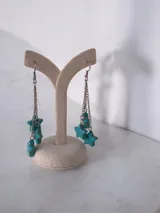 Par de caravanas colgantes con cadena plateada y dijes en forma de estrella de piedra turquesa.