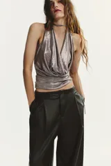 Pantalón jogger de tiro medio confeccionado en tejido efecto piel. Presenta pliegues en el delantero, bolsillos laterales, falsos bolsillos de vivo en la parte posterior y bajo acabado en elástico. Cierre frontal con cremallera, botón interior y gancho metálico.