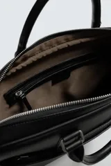 Maletín negro con textura grabada, diseño estructurado y asas de mano. Cuenta con cierre principal de cremallera, bolsillo frontal plano y bolsillo interior para dispositivos electrónicos de hasta 13 pulgadas. Incluye asa de hombro ajustable y extraíble.