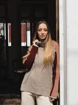 Buzo de tejido de punto con cuello alto, diseño color block en tonos beige, bordó y rosa viejo, con mangas largas y puños en contraste.