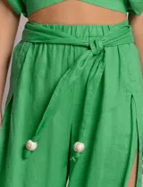 Pantalón palazzo de lino color azul, de tiro alto con cintura elastizada y cinto lazo incorporado con cuentas decorativas en las puntas. Presenta aberturas laterales pronunciadas en las piernas y corte amplio.