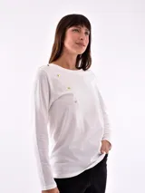 Remera negra de manga larga con cuello redondo y detalle de tachas doradas dispuestas en diagonal sobre el pecho.