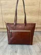 Cartera de cuero vacuno color marrón, de diseño amplio con paneles combinados de diferentes texturas y un panel central con relieve de cocodrilo. Cuenta con cierre frontal vertical y asas de hombro.