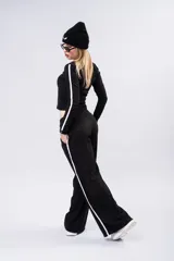 Pantalón tipo palazzo de corte amplio y fluido, color negro, con doble línea lateral blanca y cintura elástica.