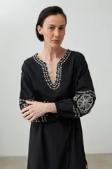 Túnica larga color crudo con bordados rojos en cuello, mangas y ruedo.