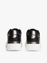 Zapatillas de plataforma Tommy Hilfiger, color negro con suela blanca. Presentan un diseño de corte bajo con cordones, confeccionadas en cuero y material sintético, con el monograma TH en el lateral y detalles metálicos en el talón.