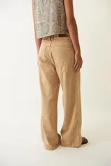 Pantalón jean color arena, de corte ancho y tiro bajo, con efecto desgastado.