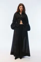 Pantalón amplio de largo maxi, color negro, con piernas anchas, cintura elástica fruncida y diseño de tela liviana con textura calada transparente.