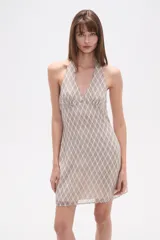 Vestido corto de poliéster, ajustado al cuerpo, con cuello halter y escote en V. Presenta un estampado de cuadros en tonos beige y negro/gris oscuro.