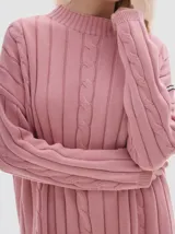 Buzo tejido de punto color beige, con cuello subido, diseño oversized y aberturas laterales en el ruedo.