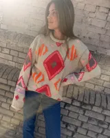 Sweater gris tejido a mano con diseño geométrico multicolor y detalles bordados, de manga larga y corte holgado.