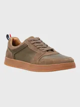 Sneaker de hombre en tonos marrones, confeccionada en una combinación de cuero y descarne. Presenta un diseño de paneles con cordones al tono, suela de goma color caramelo y un detalle de cinta tricolor en el talón.
