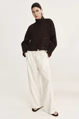 Campera corta oversize de color marrón, confeccionada en tejido de lino. Presenta cuello elevado, cierre frontal oculto con solapa y botones visibles, mangas raglán con puños abotonados, bolsillos delanteros con solapa y cordón ajustable en el bajo.