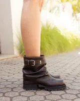 Botas cortas de cuero color marrón con efecto desgastado, diseño de caña holgada con pliegues, hebilla lateral metálica y suela track dentada.