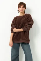 Buzo marrón de tela tipo teddy con cuello redondo y mangas largas abullonadas de nylon.