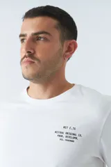 Remera verde militar de manga larga, cuello redondo y corte recto. Estampa pequeña en el pecho con texto en negro.