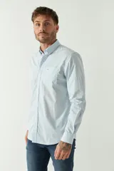 Camisa celeste de manga larga con logo bordado y bolsillo en el pecho.