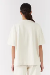 Conjunto de dos piezas color blanco off-white, compuesto por una camisa de manga corta con cuello camisero y bolsillos frontales, y un pantalón largo de corte recto y holgado.