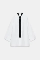 Camisa oversize de algodón con cuello redondo y solapa, manga larga con puño con vuelta y hombro caído. Presenta detalle de tablas en el delantero, cierre frontal con botones ocultos y corbata a contraste incluida.