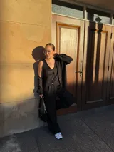 Conjunto de tres piezas en color negro compuesto por un chaleco abotonado, una camisa de manga larga y un pantalón de corte recto y tiro alto, confeccionado en tela crepé.