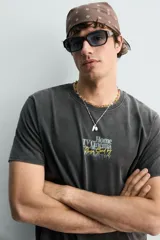 Camiseta de corte relajado con efecto lavado, cuello redondo y manga corta. Presenta estampados con textos en contraste en el frente.
