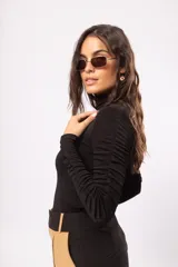 Polera negra de manga larga con cuello alto y detalle de drapeado en las mangas. Confeccionada en tela stretch suave con leve brillo.