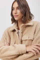 Campera tipo camisa confeccionada en tejido de sherpa, con cuello clásico, cierre frontal de botones y bolsillos delanteros con solapa.