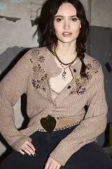 Cardigan de punto grueso en color azul, con cierre frontal de botones, mangas largas con puños de encaje blanco y detalle de bordado floral con pedrería brillante en el pecho.
