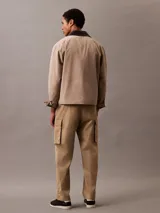Pantalón cargo color beige de algodón orgánico elástico, con cintura elástica y corte recto. Presenta bolsillos laterales, traseros y tipo cargo en las piernas.