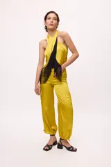 Pantalón ancho de seda color amarillo, estilo parachute o globo, con talle alto y cordones ajustables en los tobillos.