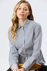 Camisa de manga larga con diseño de rayas verticales, confeccionada en mezcla de algodón, nylon y spandex. Cuenta con cuello camisero clásico y cierre frontal abotonado.