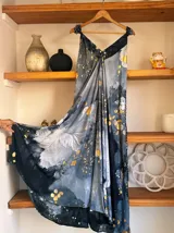 Vestido largo sin mangas con escote en V pronunciado, de corte amplio y fluido, con estampado abstracto en tonos rosados, marrones y blancos, y un cordón trenzado ajustable en la cintura.