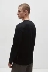 Remera deportiva de manga larga y cuello redondo, confeccionada en tejido funcional DryMove negro con aberturas cortas en el bajo.