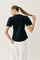 Chaqueta entallada azul marino de punto, con cuello redondo y mangas cortas abullonadas con aberturas. Cierre frontal con botones forrados a tono.
