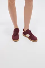 Zapatillas urbanas de color negro con suela de goma marrón, cordones negros con detalles blancos y paneles laterales.