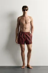 Short de baño confeccionado en tejido técnico, con diseño de rayas verticales en color verde y negro. Cuenta con cintura elástica ajustable con cordón, bolsillos laterales y bolsillo trasero con vivo, además de forro interior.