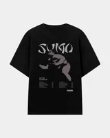 Remera negra oversize de algodón, con cuello redondo y mangas cortas. Presenta un estampado frontal en tonos grises con la palabra 'Sumo', la ilustración de un luchador y un listado de canciones inspirado en el álbum After Chabón.