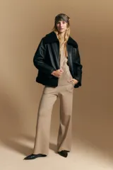 Campera tipo gamulán de cuero sintético negro, con interior y detalles de corderito sintético al tono en cuello y ruedo. Presenta cierre frontal metálico y diseño de silueta relajada.