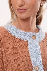 Saco marrón de tejido de punto con detalles en relieve y borde celeste. Tiene cuello redondo, cierre con botones de madera y mangas largas.