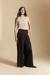 Top sin mangas de color negro con cuello alto y diseño drapeado en el frente. Confeccionado en una tela suave con acabado levemente satinado y silueta fluida.