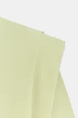 Top de punto color verde claro con cuello redondo, manga corta, hombreras marcadas y pliegues decorativos en la parte frontal.