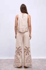 Blusa color beige con bordados de palmeras y conchas marinas en color marrón.