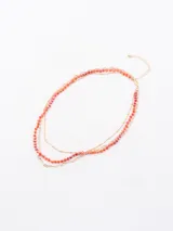 Collar dorado de tres hilos, dos de cadena y uno con cuentas de color naranja y rosa.