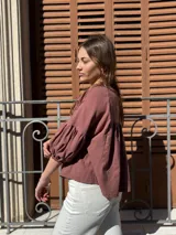 Blusa color chocolate de diseño holgado, con cuello redondo, frunce frontal y mangas abullonadas con puños ajustados.