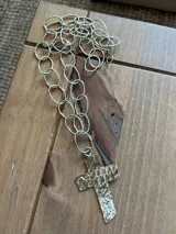 Collar plateado con eslabones ovalados y dije de cruz dorada con textura martillada.