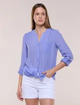 Blusa violeta de corte fluido, con cuello mao, escote en V y bolsillo plaqué en el pecho. Presenta mangas largas regulables con presilla y un lazo frontal para anudar en la cintura.