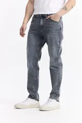 Pantalón de jean con corte slim, tiro medio y cierre frontal con botón y cremallera. Presenta un lavado gris con efecto desgastado y costuras reforzadas.