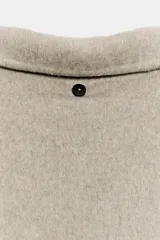 Cazadora de lana con diseño de doble capa, cuello solapa y manga larga. Presenta cierre frontal con botones y bolsillos de vivo en el delantero.