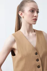 Chaleco sastrero color marrón oscuro, con escote en V, cierre frontal de botones y pinzas de entalle.